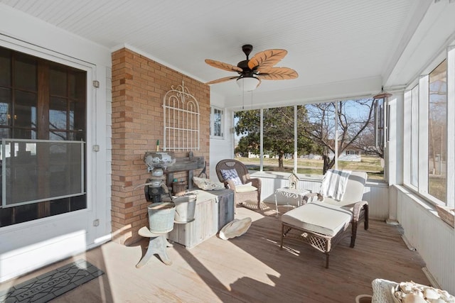 sunroom / solarium with a ceiling fan, wood finished floors, plenty of natural light, crown molding, and brick wall