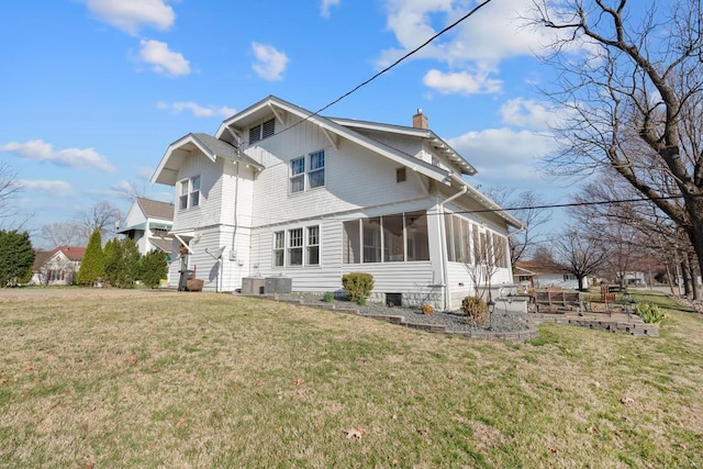 view of side of property featuring a chimney, a sunroom, and a lawn