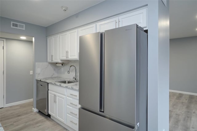 572 Coeur De Royale Dr Unit 108, Saint Louis, MO 63141 - kitchen featuring appliances with stainless steel finishes, a sink, white cabinets, light stone counters, and light wood-style flooring