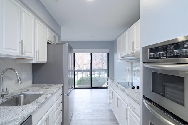 572 Coeur De Royale Dr Unit 108, Saint Louis, MO 63141 - kitchen featuring a sink, appliances with stainless steel finishes, white cabinets, light stone countertops, and light wood-style flooring