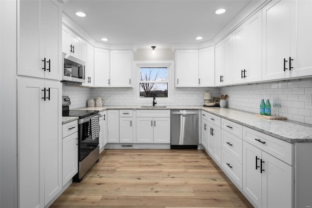 4 Tiger Dr, Wentzville, MO 63385 - kitchen with appliances with stainless steel finishes, a sink, light wood-style floors, backsplash, and white cabinetry