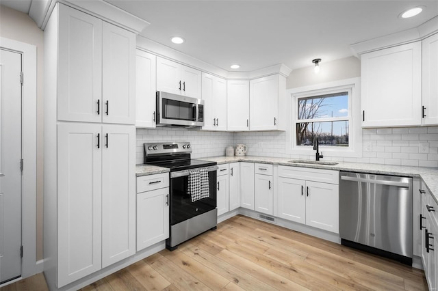 4 Tiger Dr, Wentzville, MO 63385 - kitchen with appliances with stainless steel finishes, a sink, backsplash, white cabinetry, and recessed lighting