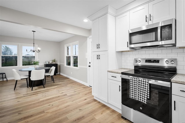 4 Tiger Dr, Wentzville, MO 63385 - kitchen featuring stainless steel appliances, light wood-style flooring, decorative backsplash, a chandelier, and baseboards