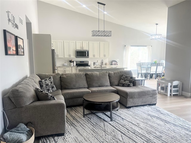 1564 Mandy Ln, Barnhart, MO 63012 - living room featuring high vaulted ceiling, light wood-style flooring, baseboards, and a chandelier