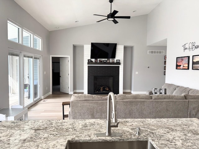 1564 Mandy Ln, Barnhart, MO 63012 - living room featuring high vaulted ceiling, light wood-style flooring, a fireplace, a ceiling fan, and baseboards