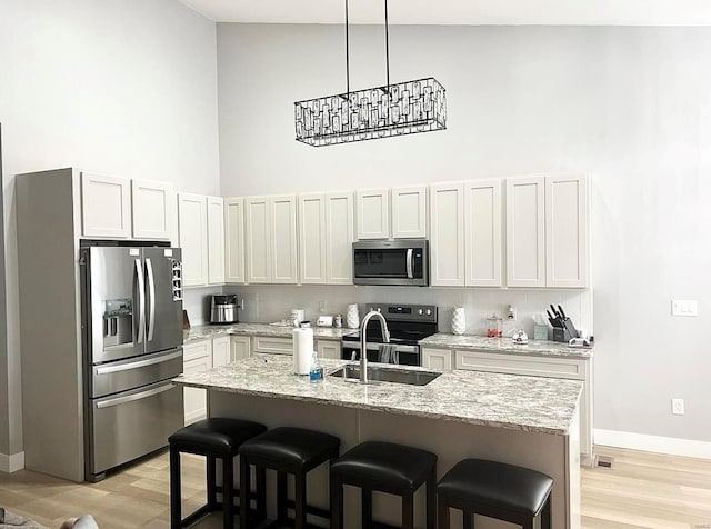 1564 Mandy Ln, Barnhart, MO 63012 - kitchen with appliances with stainless steel finishes, a sink, a high ceiling, a breakfast bar, and light wood-type flooring