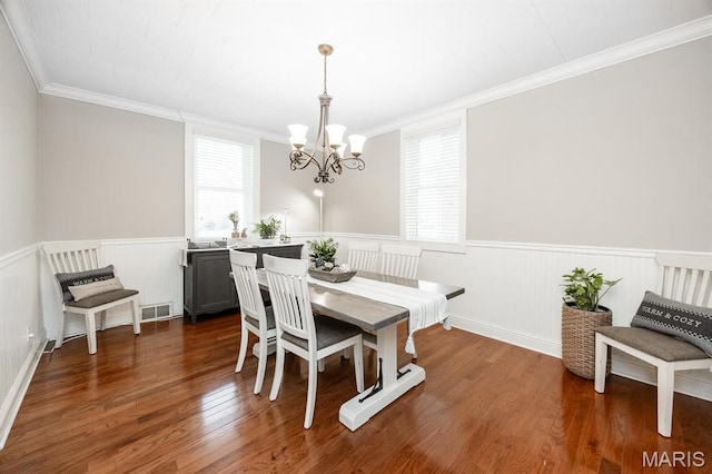dining space with a chandelier, a wainscoted wall, crown molding, and wood finished floors