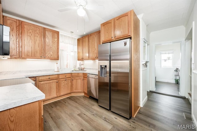 kitchen with stainless steel appliances, ceiling fan, light wood-style flooring, a sink, and light countertops