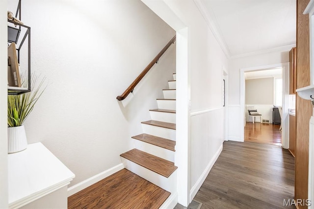stairs with crown molding and wood finished floors