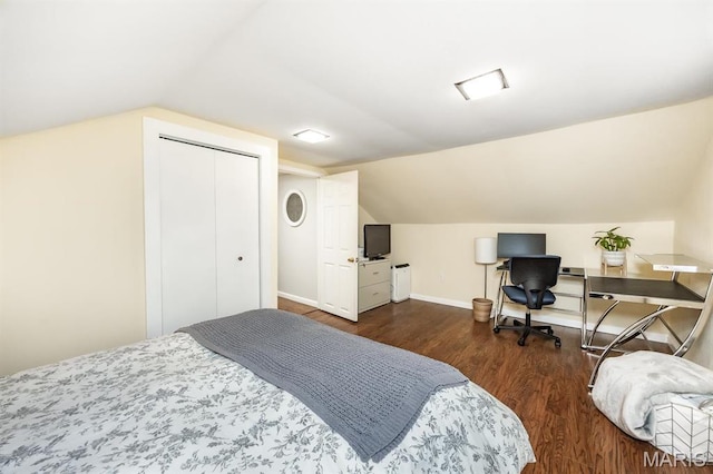 bedroom with vaulted ceiling, wood finished floors, baseboards, and a closet