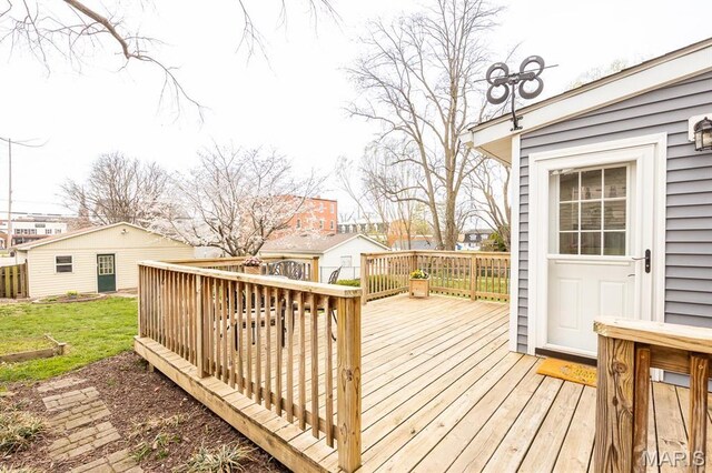 wooden deck featuring a lawn, a residential view, and an outbuilding