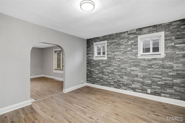 5537 Helen Ave, Saint Louis, MO 63136 - spare room featuring arched walkways, wood finished floors, baseboards, and a textured ceiling