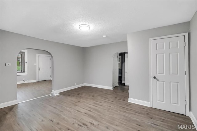 5537 Helen Ave, Saint Louis, MO 63136 - spare room featuring arched walkways, wood finished floors, a textured ceiling, and baseboards