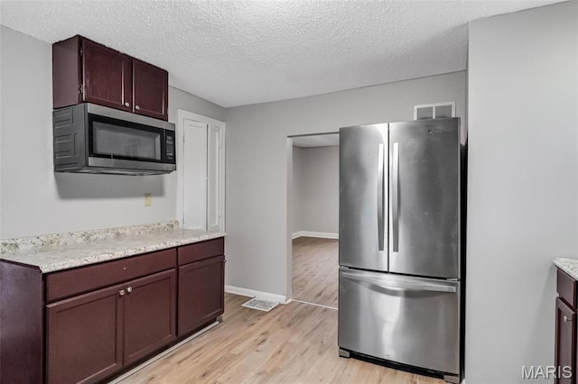 5537 Helen Ave, Saint Louis, MO 63136 - kitchen with stainless steel appliances, light countertops, light wood finished floors, a textured ceiling, and baseboards
