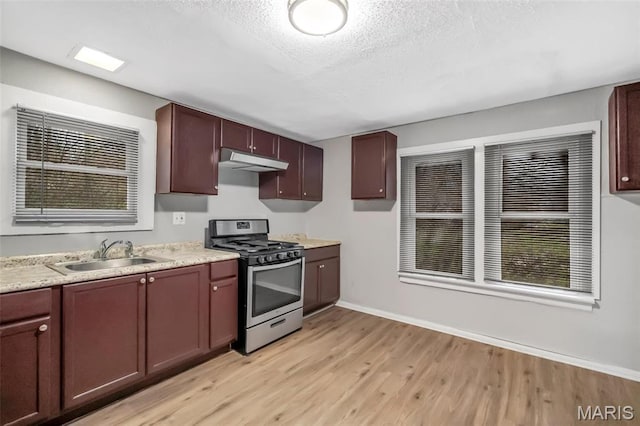 5537 Helen Ave, Saint Louis, MO 63136 - kitchen with gas range, a sink, under cabinet range hood, light wood finished floors, and baseboards