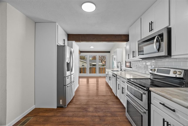 7 Beavertail Ct, Florissant, MO 63033 - kitchen with appliances with stainless steel finishes, dark wood-style flooring, backsplash, a sink, and light countertops