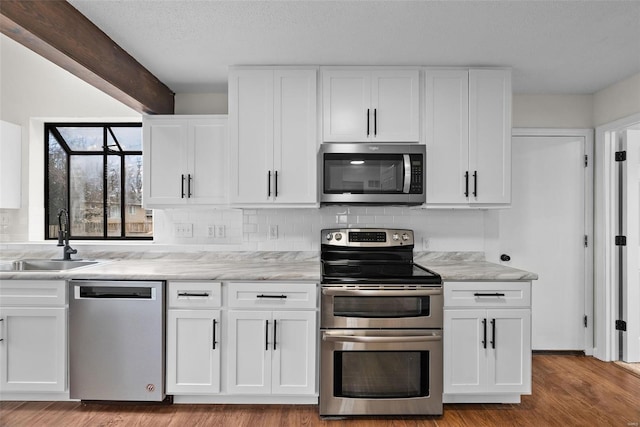 7 Beavertail Ct, Florissant, MO 63033 - kitchen with appliances with stainless steel finishes, a sink, decorative backsplash, white cabinetry, and a textured ceiling