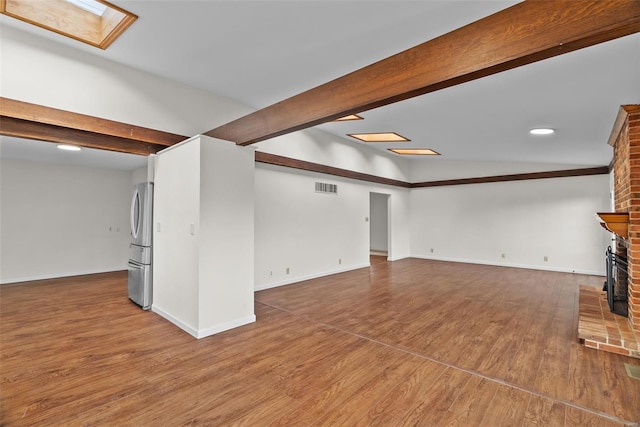 7 Beavertail Ct, Florissant, MO 63033 - unfurnished living room featuring beamed ceiling, wood finished floors, a brick fireplace, baseboards, and recessed lighting