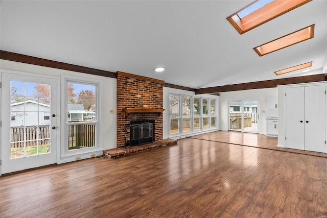 7 Beavertail Ct, Florissant, MO 63033 - unfurnished living room with plenty of natural light, a skylight, wood finished floors, a brick fireplace, and lofted ceiling