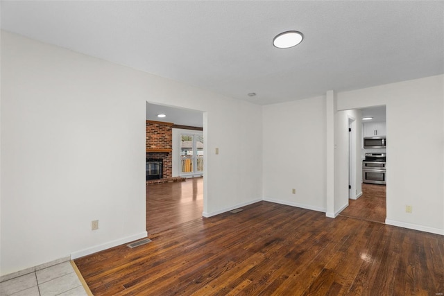 7 Beavertail Ct, Florissant, MO 63033 - spare room with hardwood / wood-style floors, baseboards, and a brick fireplace