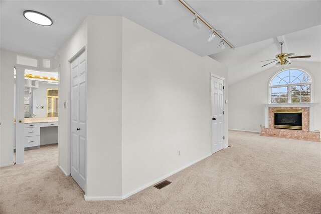 7 Beavertail Ct, Florissant, MO 63033 - unfurnished living room with rail lighting, light carpet, a glass covered fireplace, a ceiling fan, and baseboards