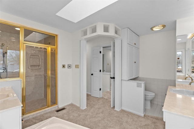 7 Beavertail Ct, Florissant, MO 63033 - full bath with vanity, a stall shower, a skylight, toilet, and tile walls