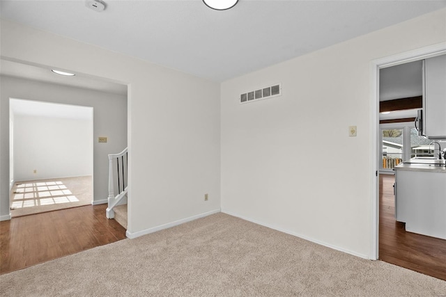 7 Beavertail Ct, Florissant, MO 63033 - spare room featuring carpet flooring, a sink, stairway, and baseboards