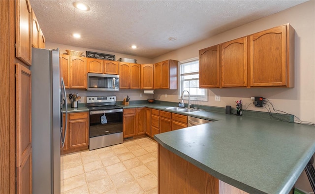 1205 Britt Ln, Rolla, MO 65401 - kitchen with stainless steel appliances, a peninsula, a sink, dark countertops, and a textured ceiling