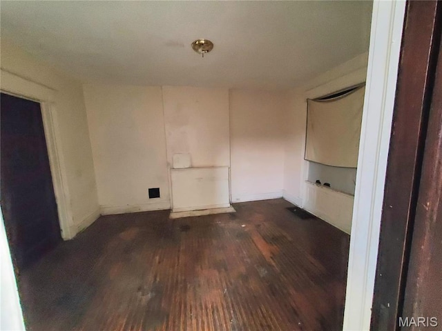 empty room with dark wood-style flooring and baseboards