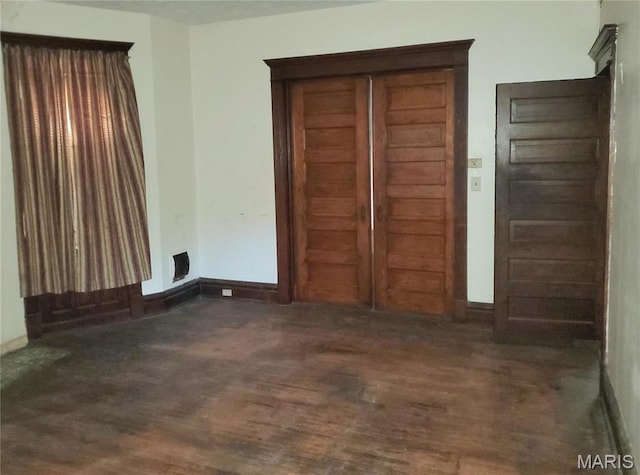 unfurnished living room featuring wood finished floors and baseboards
