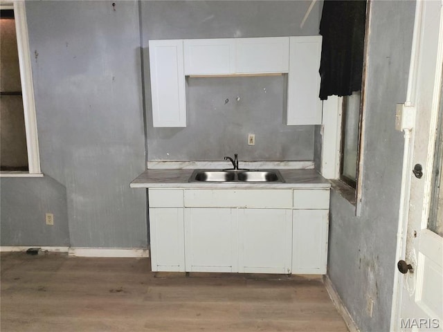 kitchen with a sink, light wood-style floors, white cabinetry, and light countertops