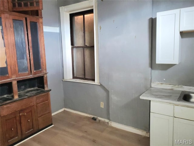 unfurnished dining area featuring wood finished floors, baseboards, and a sink
