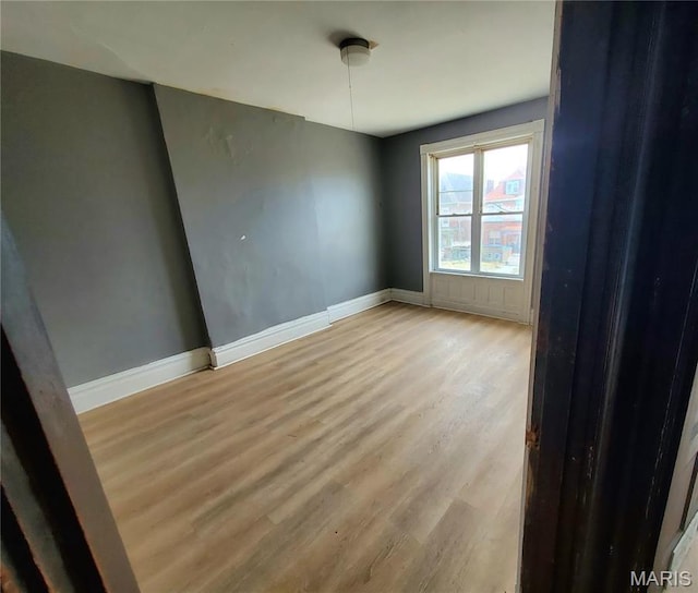 spare room featuring light wood finished floors and baseboards