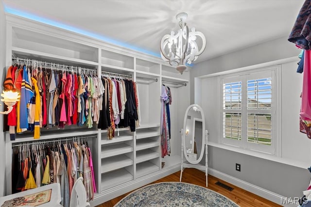 spacious closet with a chandelier and wood finished floors