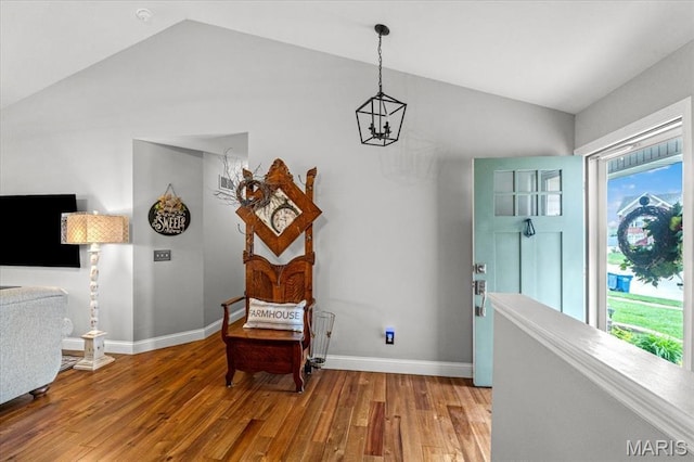 living area with vaulted ceiling, wood finished floors, baseboards, and a chandelier