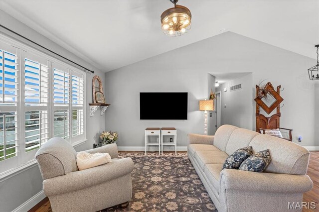 living room featuring lofted ceiling, baseboards, and wood finished floors