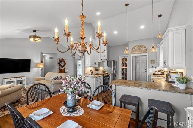 dining space with dark wood-type flooring, high vaulted ceiling, and a chandelier