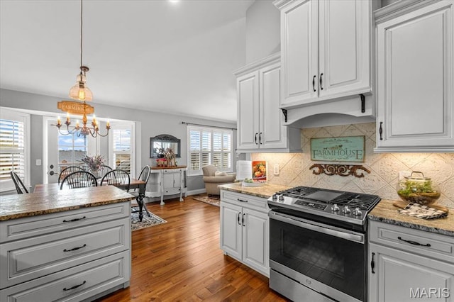 kitchen featuring gas range, a chandelier, decorative backsplash, and white cabinets