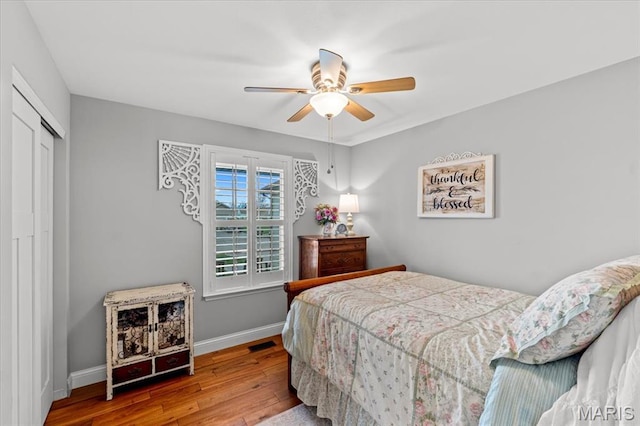 bedroom with hardwood / wood-style flooring, baseboards, a closet, and a ceiling fan