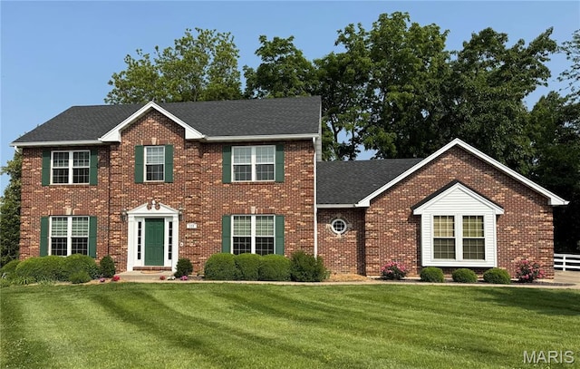 123 El Rancho Dr, Hannibal, MO 63401 - colonial house featuring brick siding, a front lawn, and roof with shingles