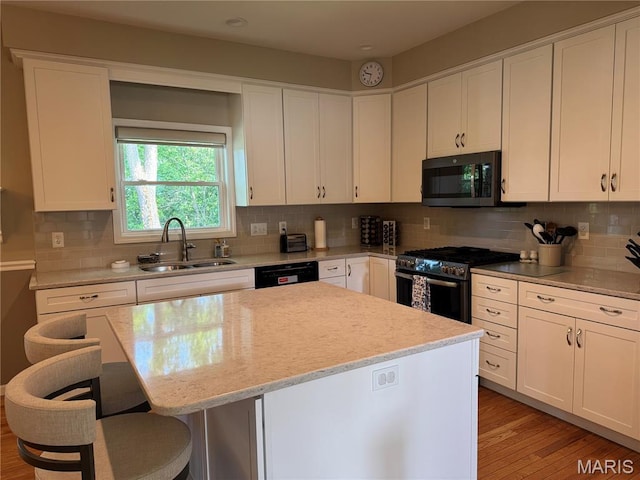 123 El Rancho Dr, Hannibal, MO 63401 - kitchen with stainless steel range with gas cooktop, a sink, a kitchen bar, and white cabinets