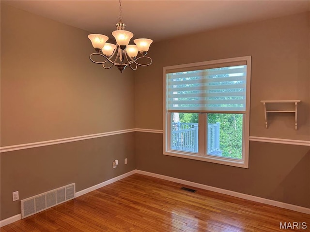 123 El Rancho Dr, Hannibal, MO 63401 - spare room featuring wood finished floors, baseboards, and a chandelier