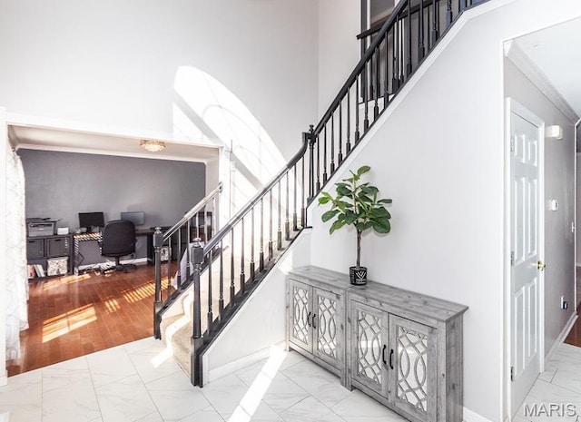 staircase with marble look tile flooring, crown molding, and baseboards