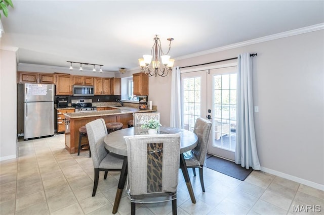dining space with a chandelier, crown molding, baseboards, track lighting, and french doors