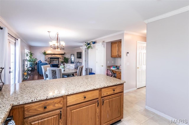 9 Shelby Crest Ct, Ofallon, MO 63366 - kitchen with brown cabinetry, a chandelier, light stone counters, crown molding, and light tile patterned floors