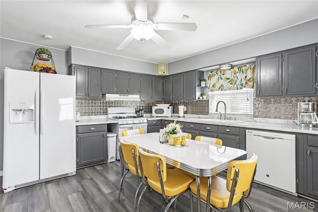 kitchen featuring white appliances, under cabinet range hood, gray cabinetry, and light countertops
