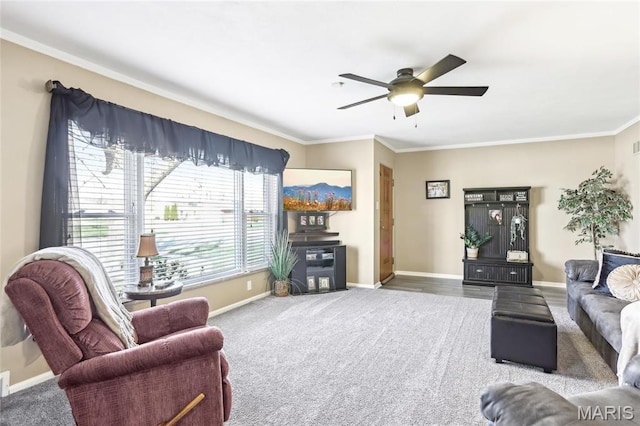 carpeted living area with a ceiling fan, baseboards, and ornamental molding