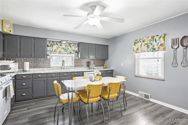 kitchen featuring white appliances, a sink, gray cabinetry, and backsplash