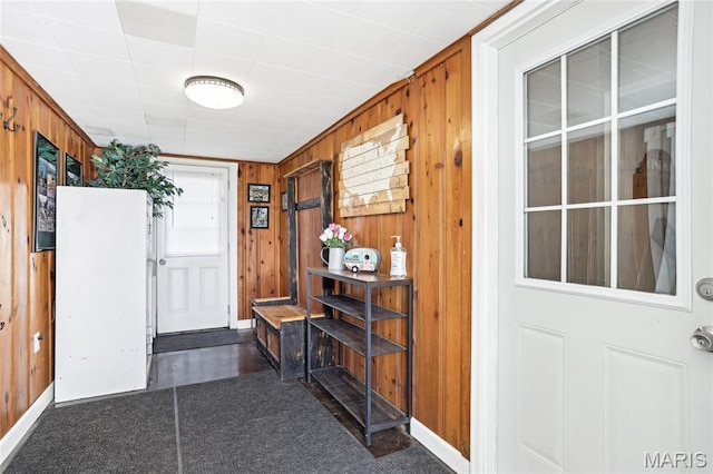 doorway to outside featuring wooden walls and baseboards