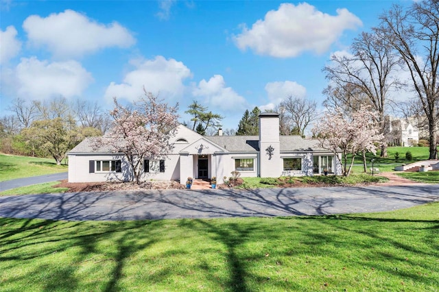 rear view of property with a chimney and a lawn